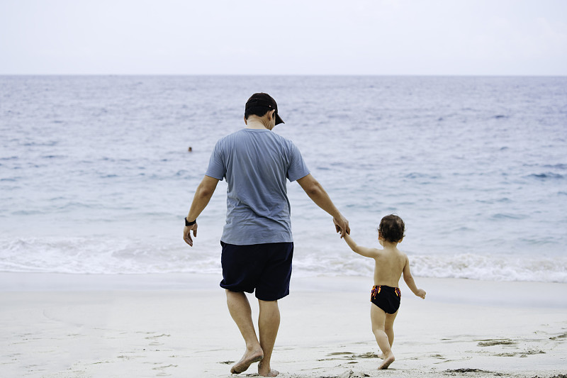亚洲男人在沙滩上教他的孩子走路图片下载