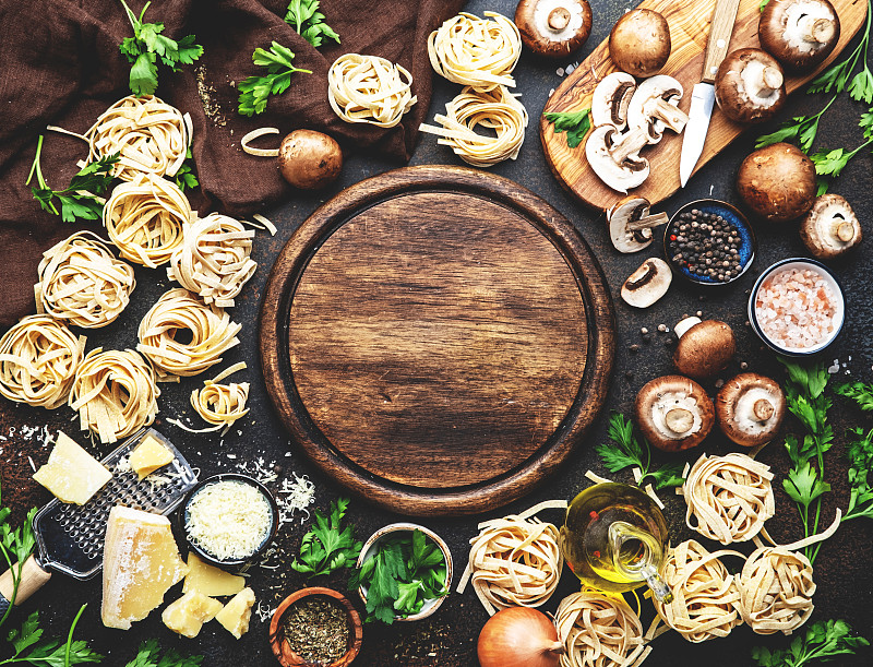 食品的背景。未煮熟的意大利面，棕色蘑菇，蔬菜，奶酪和美味的烹饪材料在棕色桌子背景，俯视图图片下载