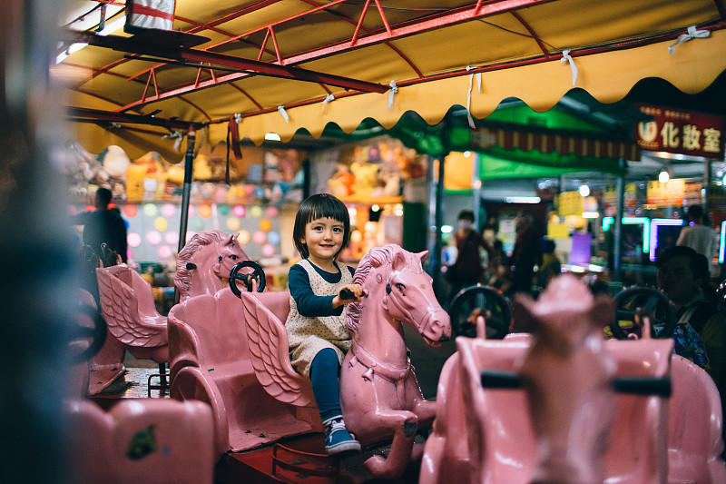 可爱的女孩在夜市享受旋转木马，台湾图片素材