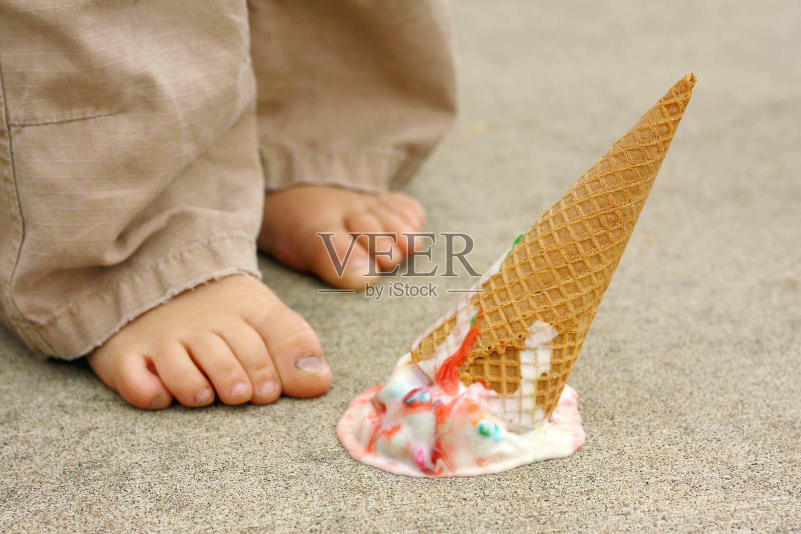小孩子会用脚把冰淇淋蛋卷掉下来照片摄影图片