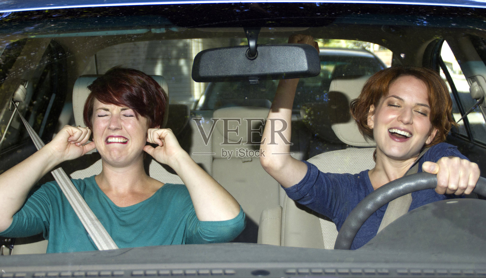 一个女人在唱歌，另一个女人在车里捂着耳朵照片摄影图片