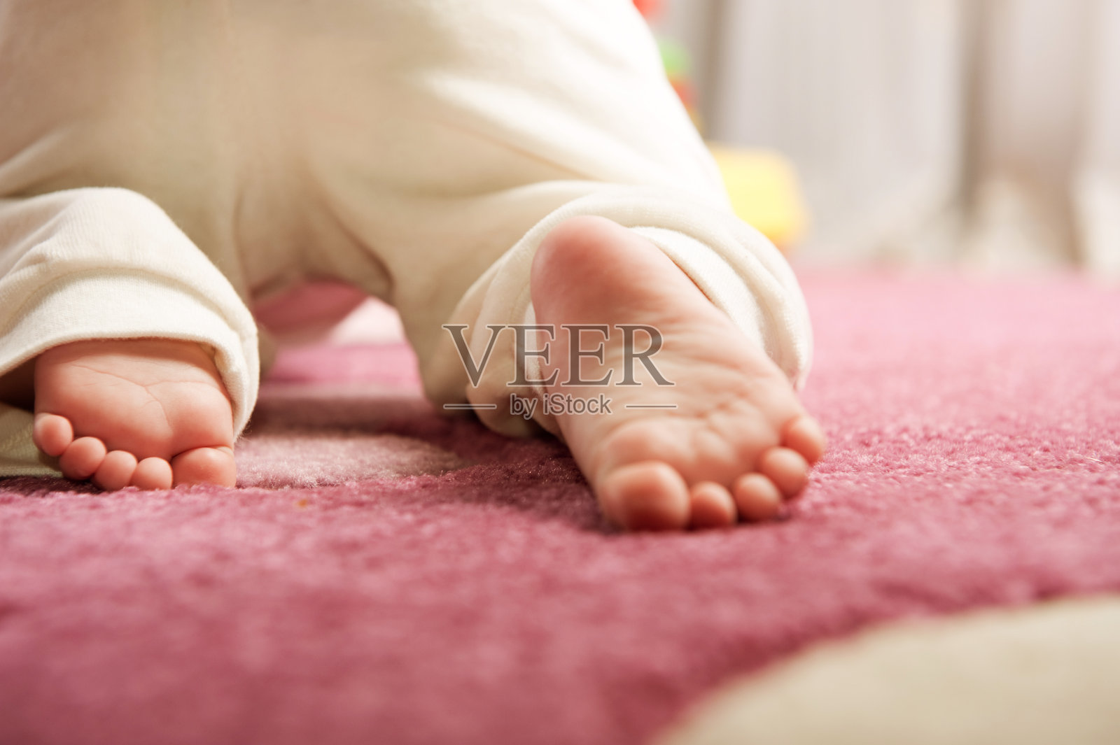 一个婴儿的脚在粉红色的地毯上爬行照片摄影图片
