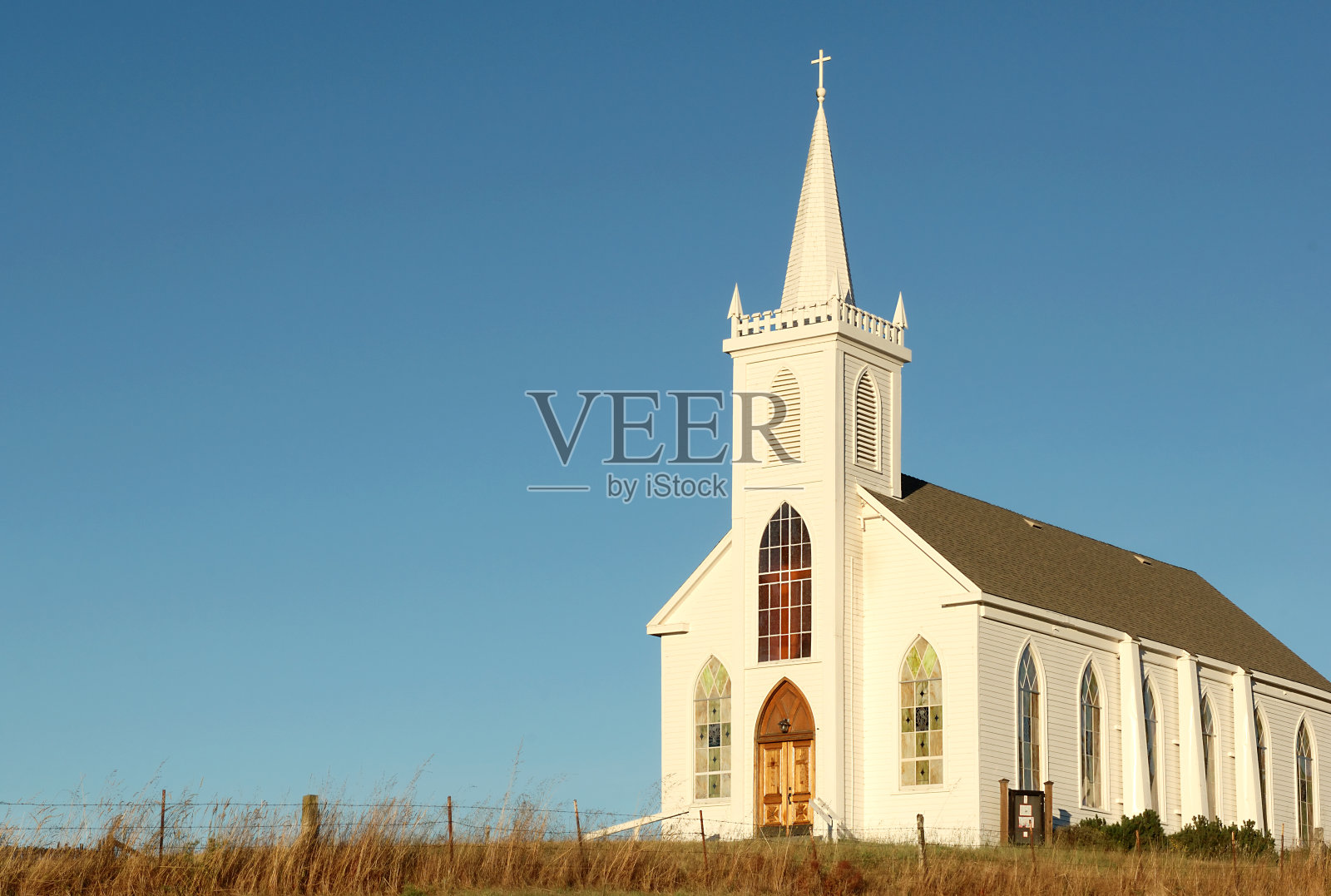 无云的天空，草地上白色的乡村教堂照片摄影图片