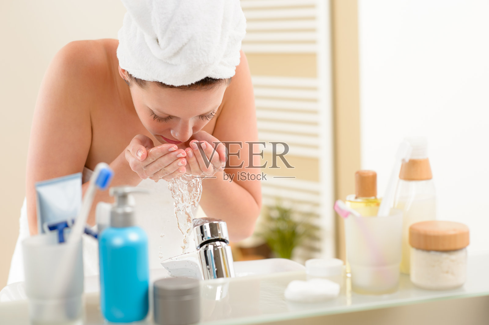在浴室水槽上洗脸的女人照片摄影图片