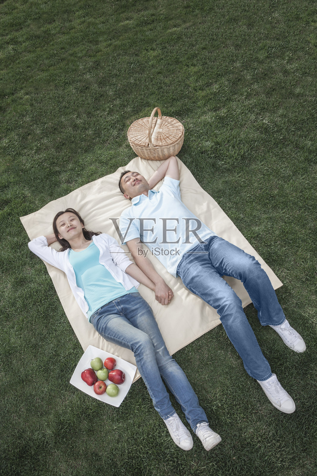 一对夫妇躺在野餐毯子上。照片摄影图片