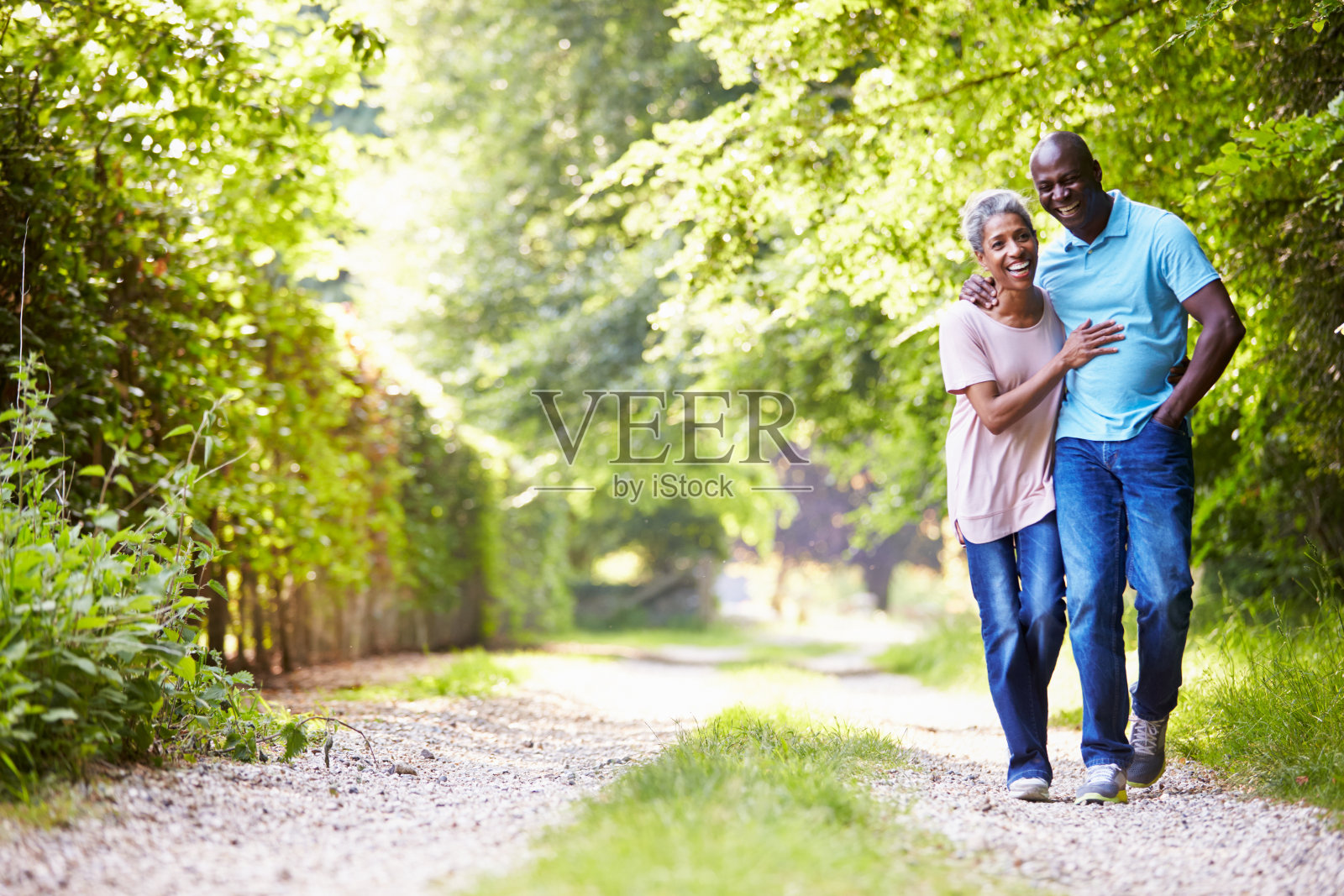 一对老夫妇走在有树的砾石小路上照片摄影图片