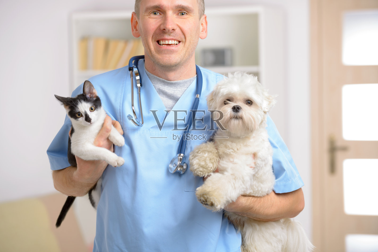 穿着蓝色制服的男兽医抱着猫和狗照片摄影图片