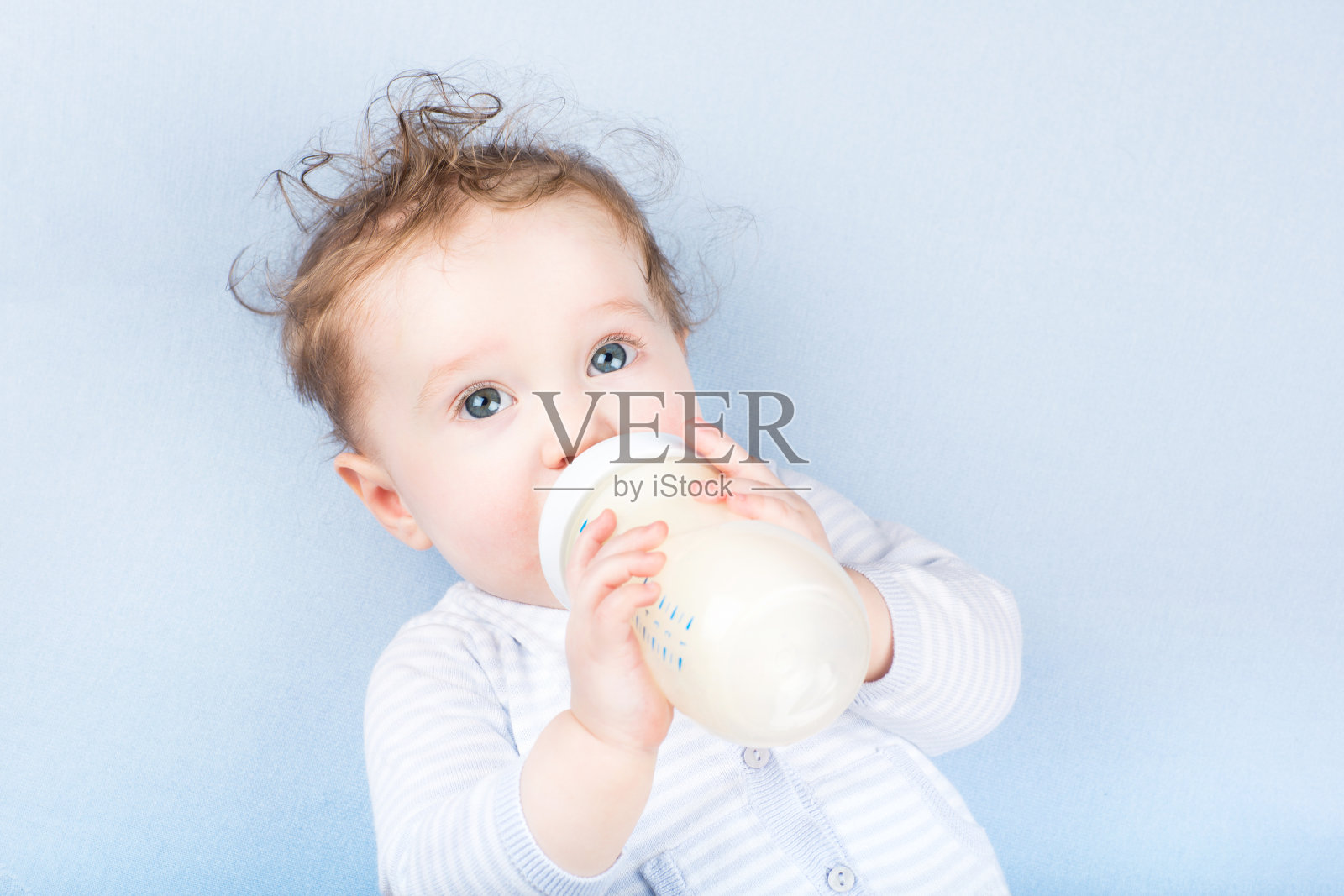 可爱的婴儿和奶瓶上的蓝色毯子照片摄影图片