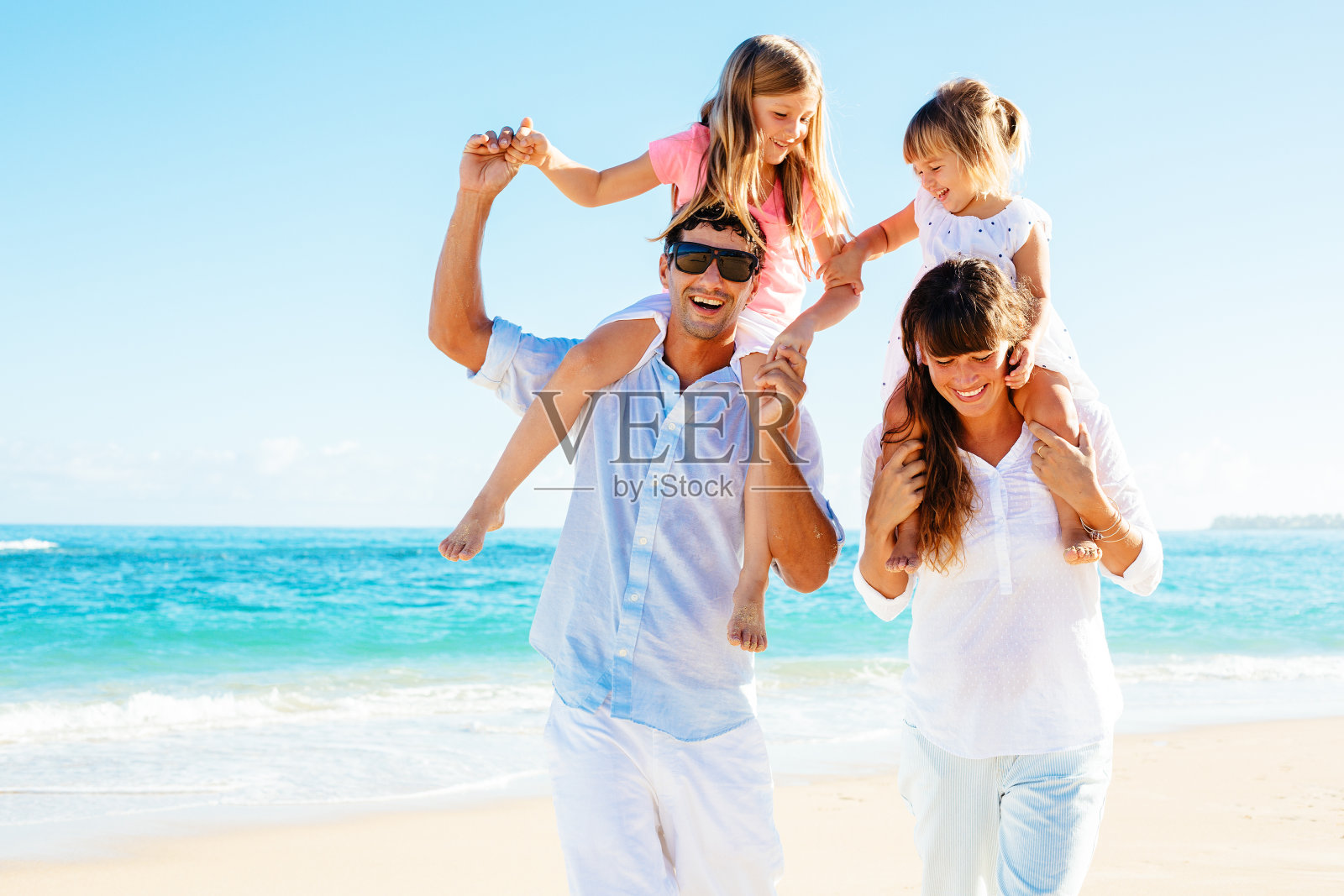 妈妈，爸爸和两个孩子在海滩上玩照片摄影图片