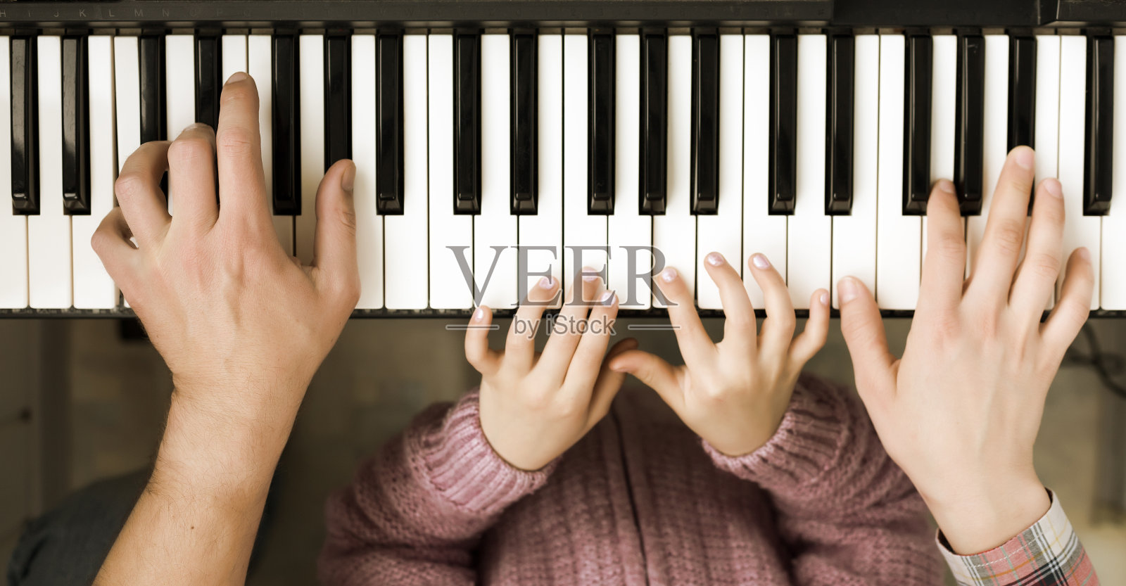 钢琴键盘俯视图和手的孩子，母亲，父亲照片摄影图片