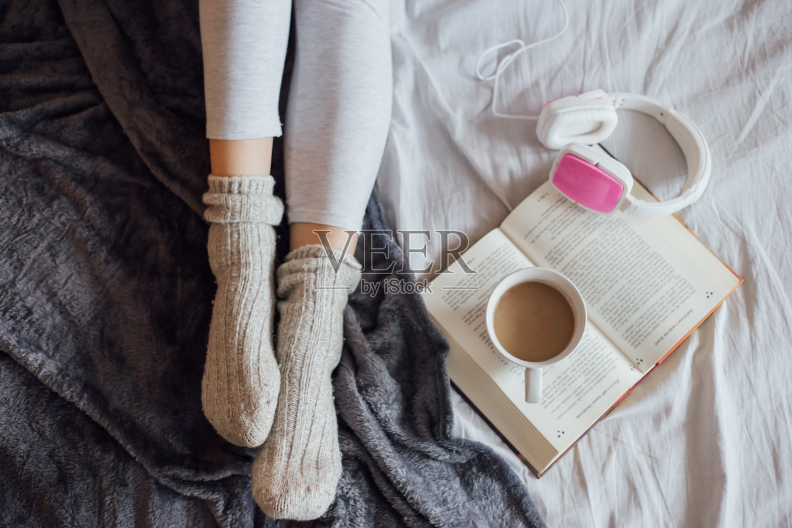 女人躺在床上，拿着书，咖啡和耳机照片摄影图片