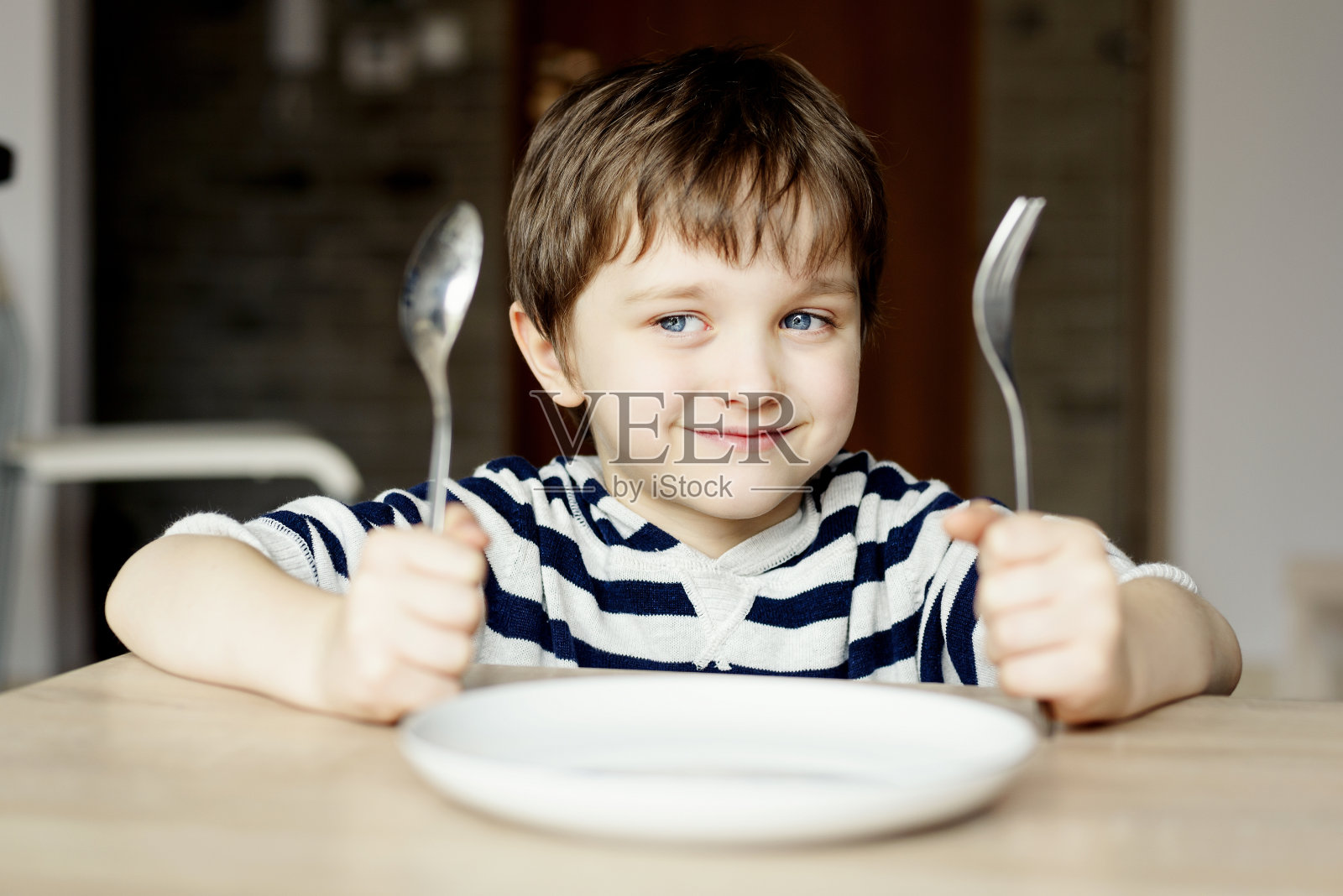 快乐的小男孩等着吃晚饭。照片摄影图片