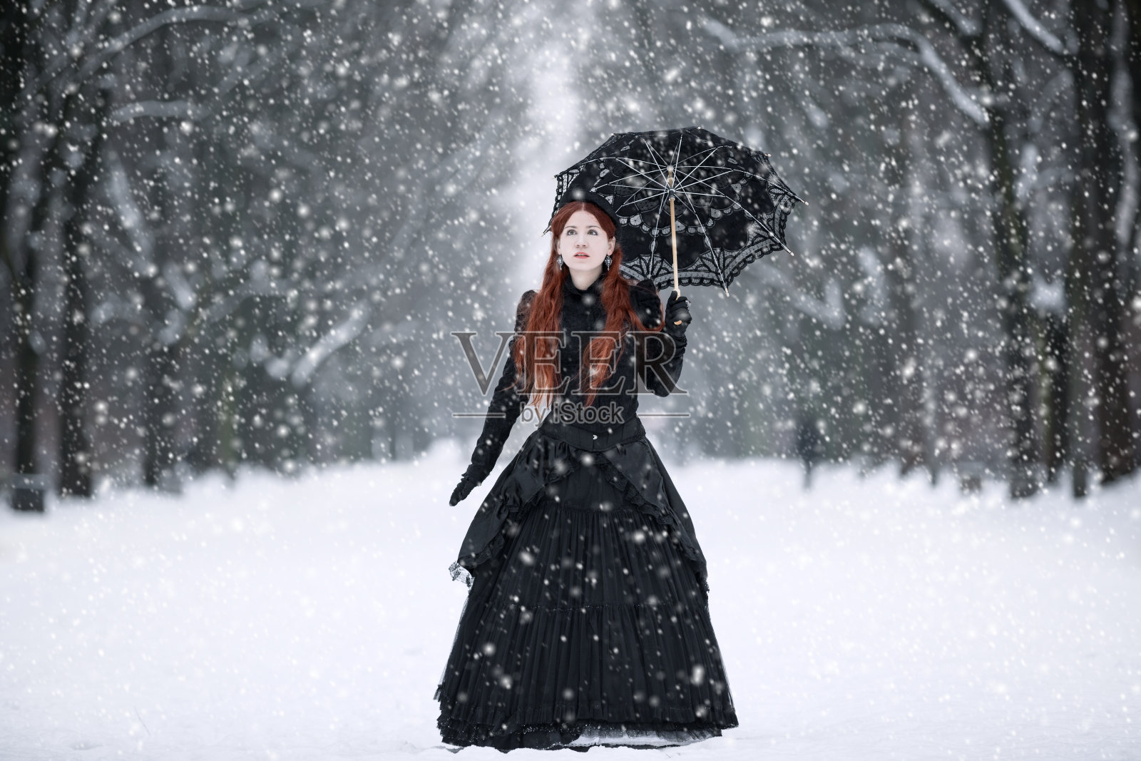 冬天公园里穿着黑色维多利亚式连衣裙的女人照片摄影图片
