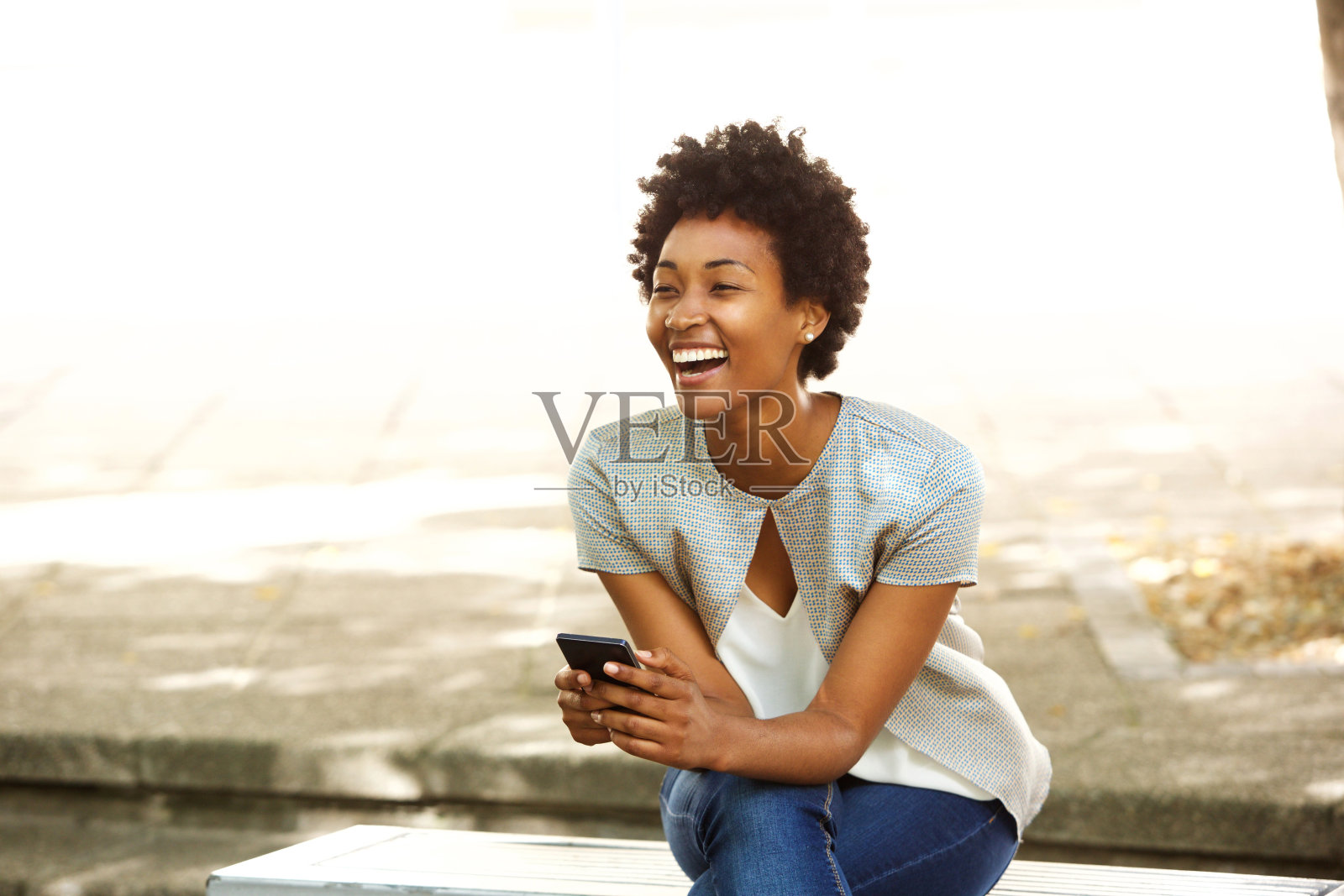 美丽年轻的非洲女人在外面微笑着拿着手机照片摄影图片