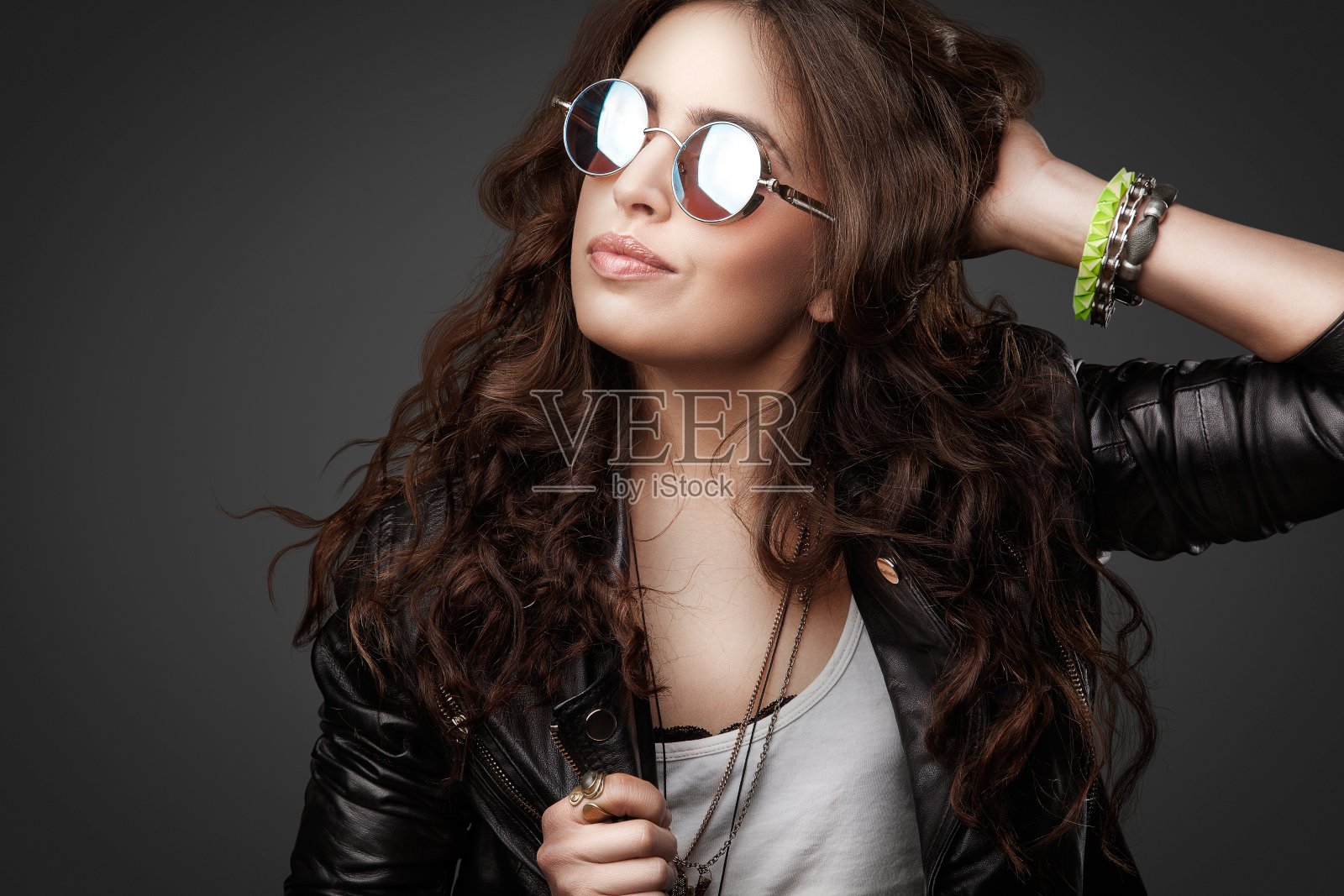 漂亮的年轻时髦的女孩，穿着皮夹克和圆形太阳镜照片摄影图片