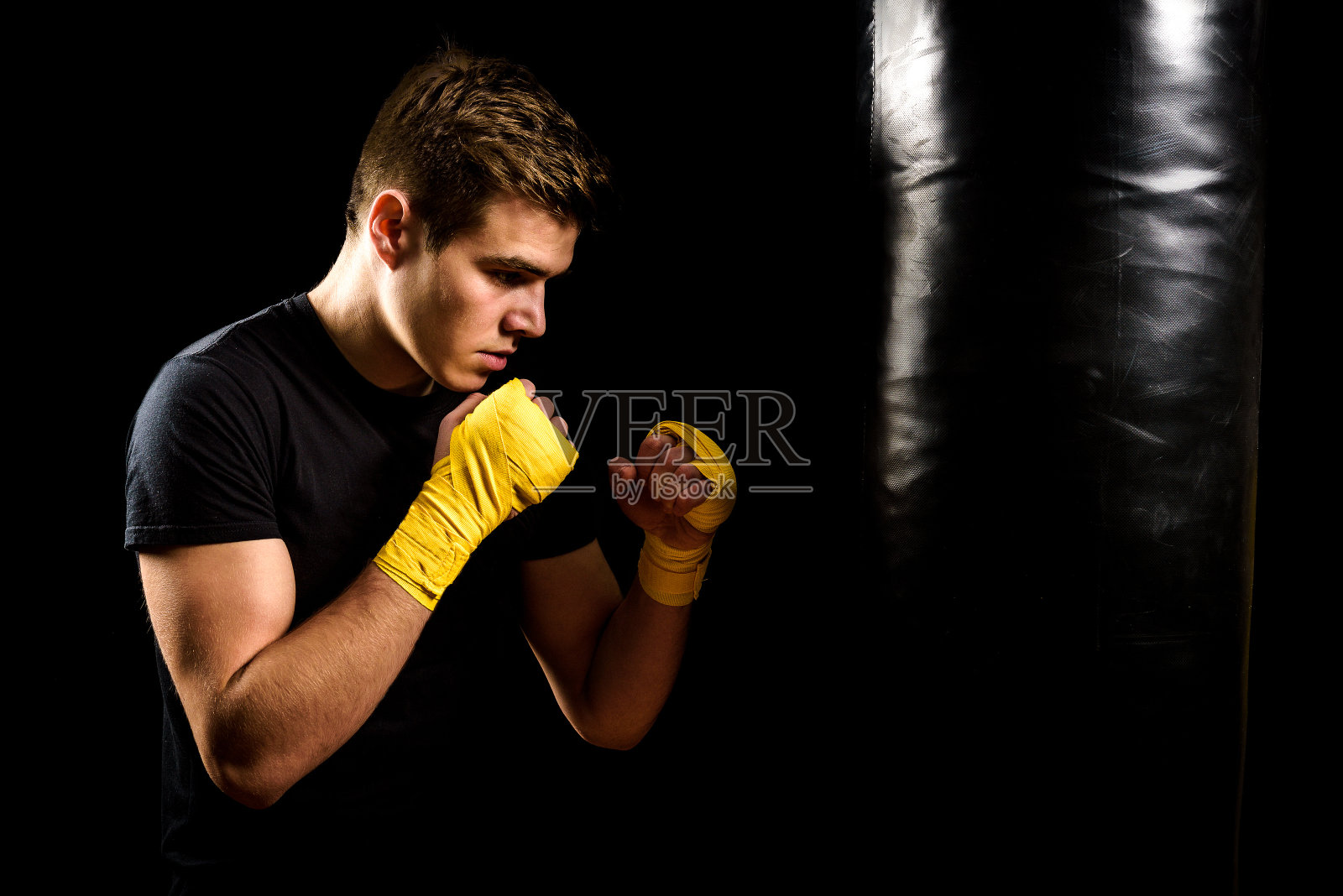 穿着拳击包的人正在训练和打击沉重的袋子。照片摄影图片