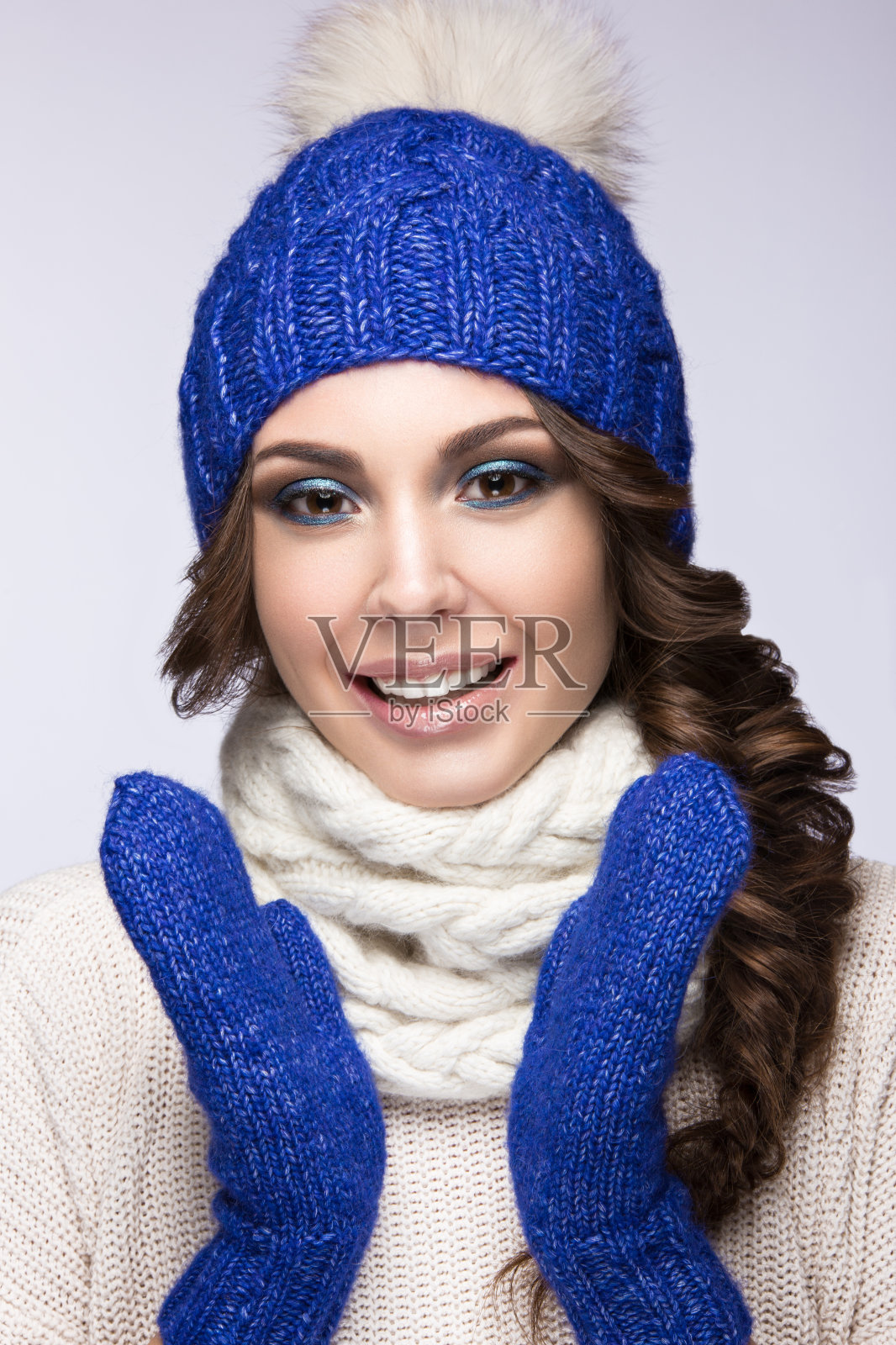 美丽的女孩与温柔的化妆，微笑在蓝色针织帽。照片摄影图片