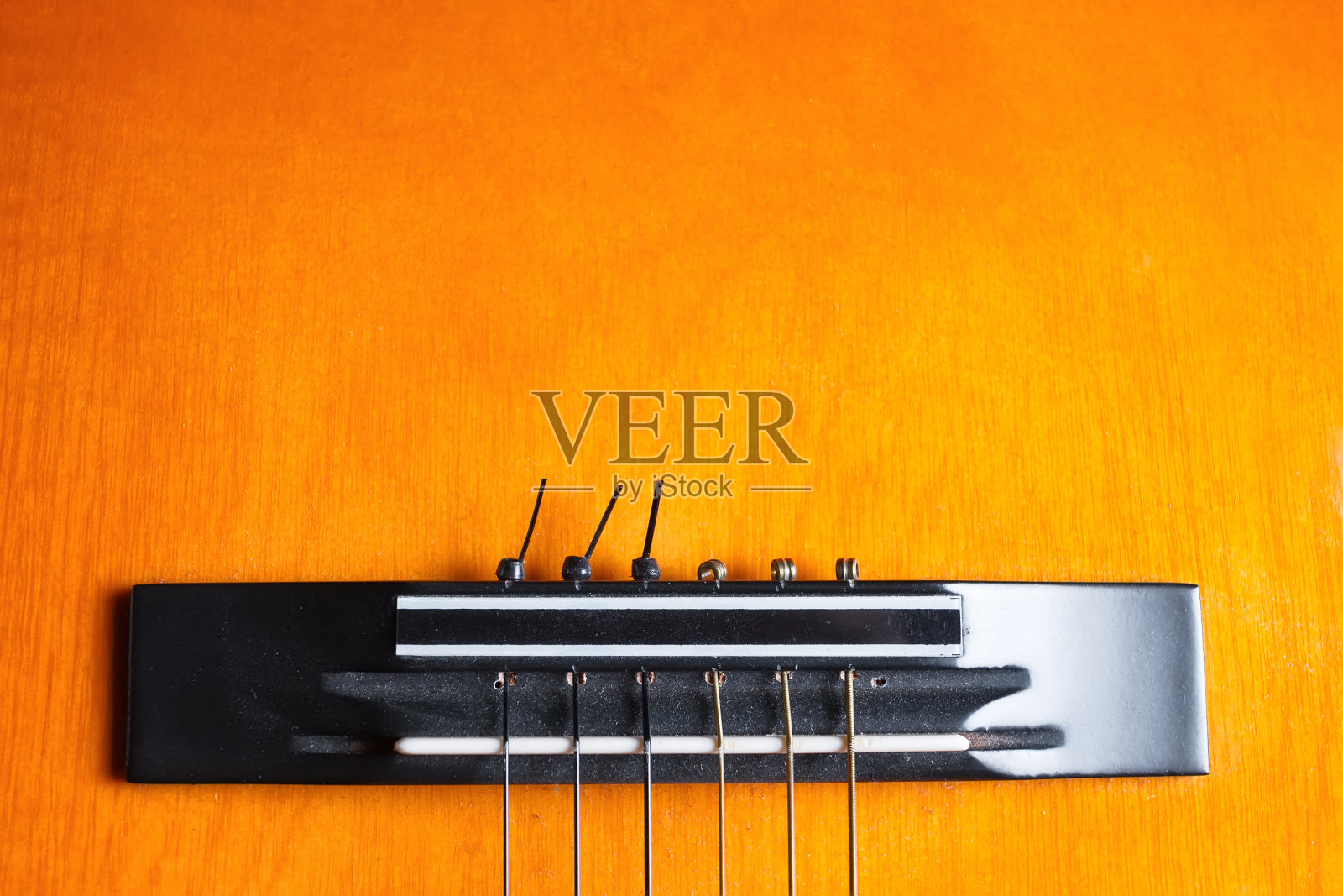 黄色和橙色吉他的琴桥和琴弦。照片摄影图片