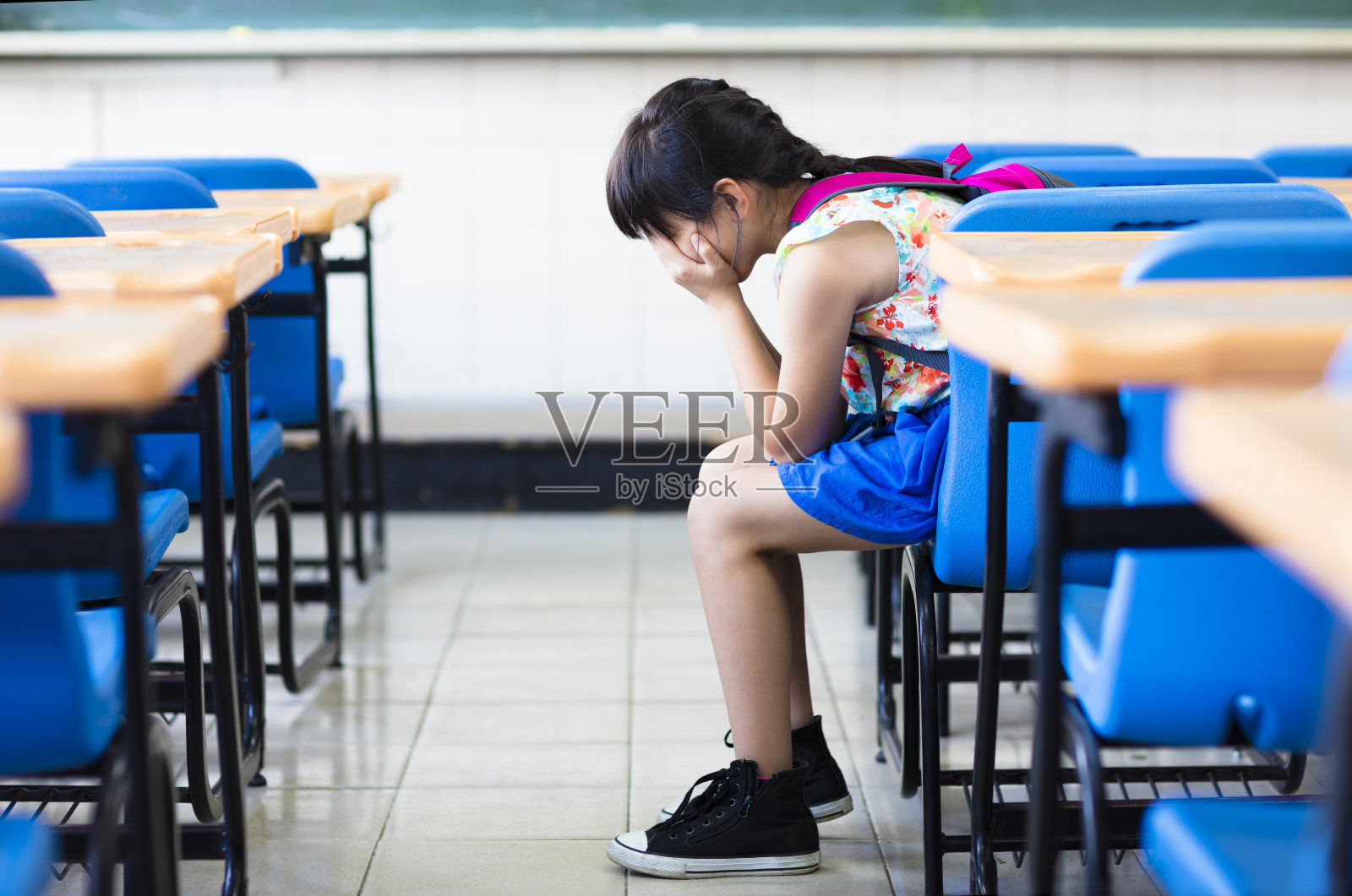 悲伤的女孩坐在教室里思考照片摄影图片