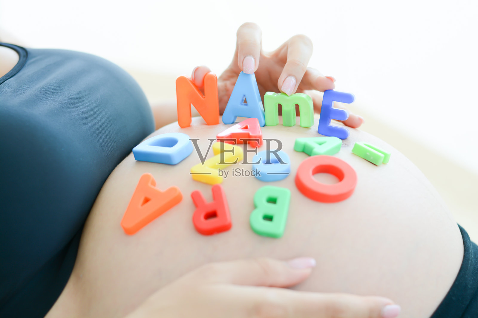 准妈妈在她怀孕的肚子上拼写名字照片摄影图片