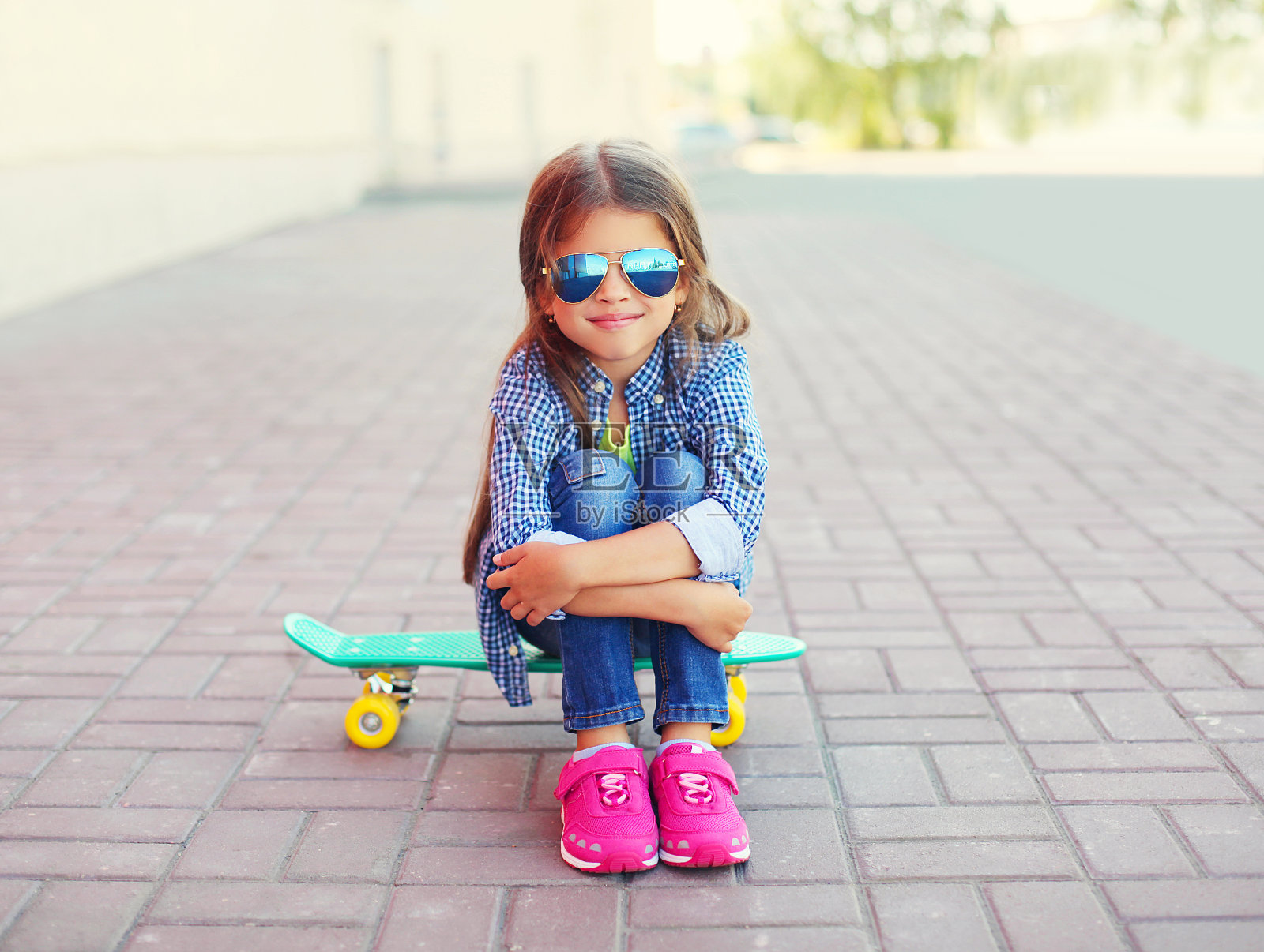 快乐的微笑时尚的小女孩坐在滑板上照片摄影图片