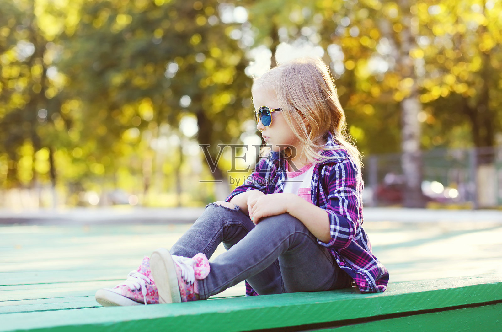 孩子戴着太阳镜，穿着格子衬衫坐在城市里照片摄影图片