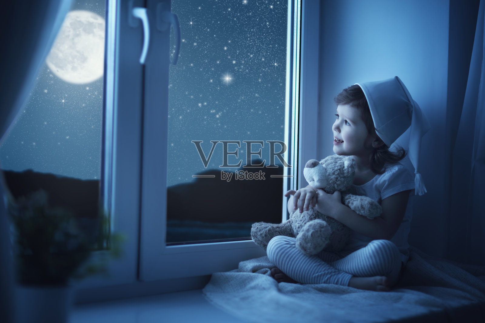 小女孩在窗前做着梦，欣赏着繁星点点的天空照片摄影图片