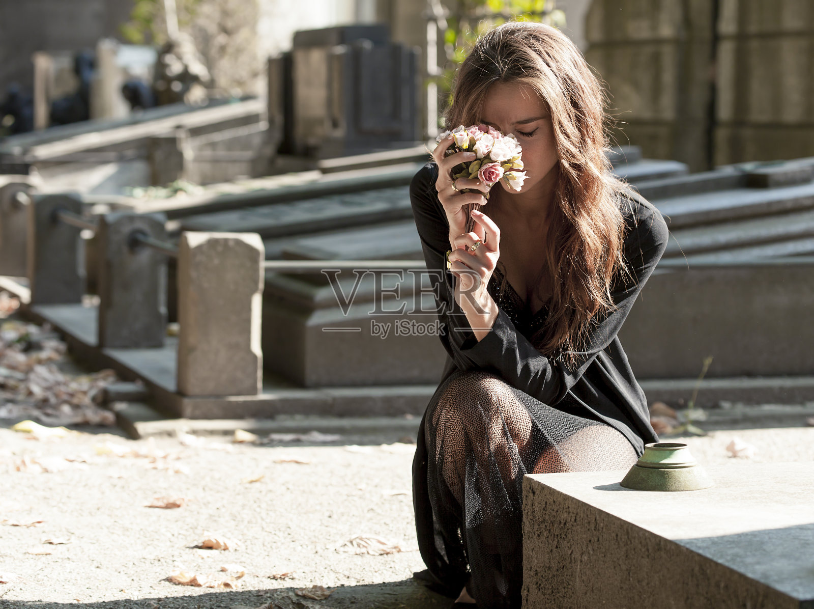 一个悲伤的女人拿着一束花站在墓前照片摄影图片