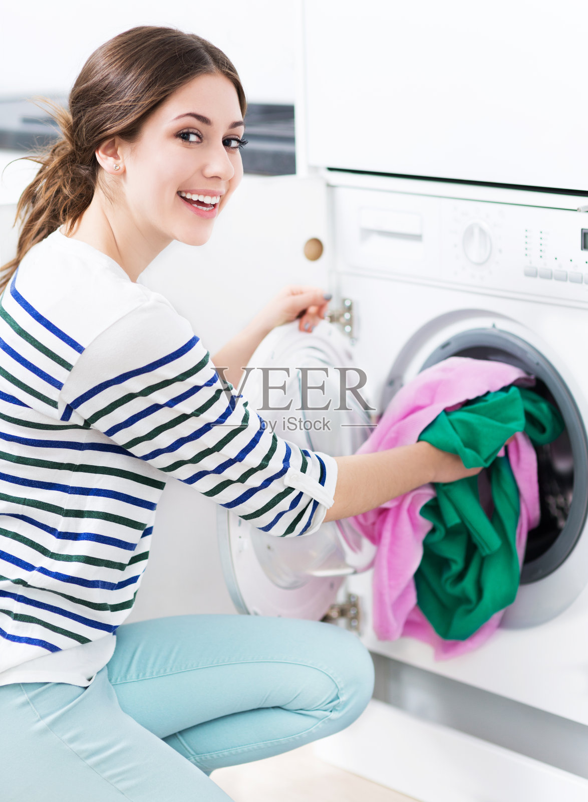 一个女人把衣服放进洗衣机里照片摄影图片