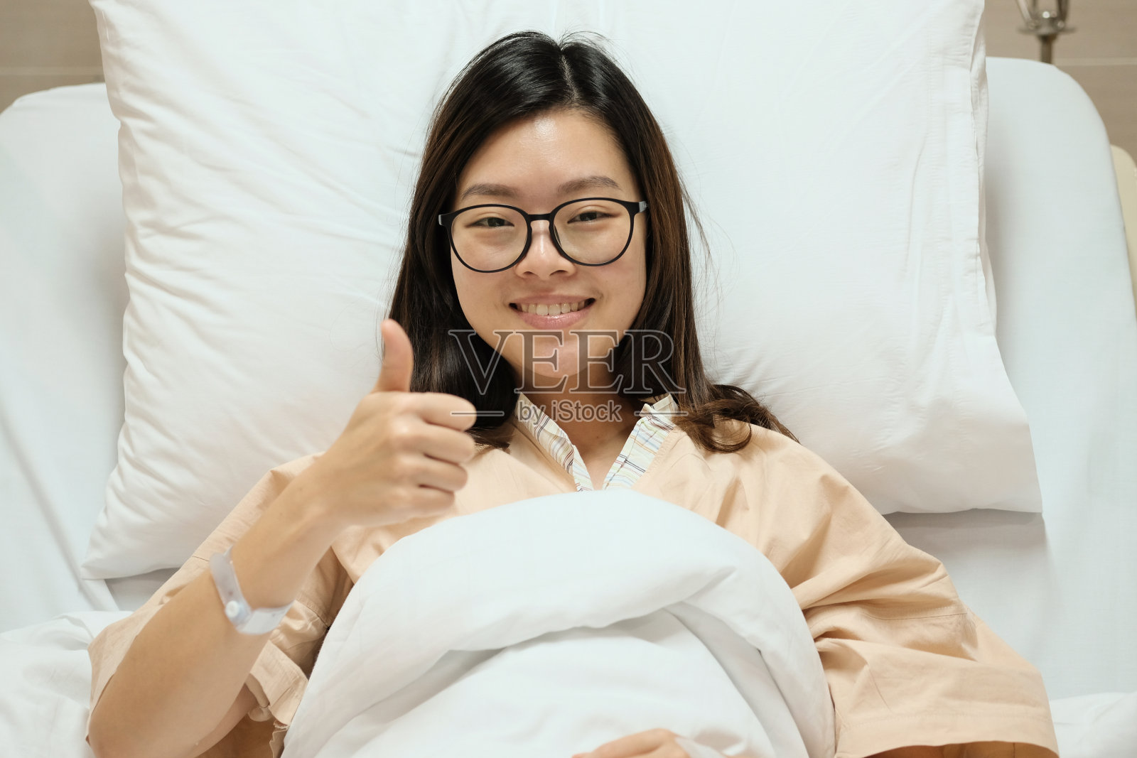 亚洲病人女孩在病床上竖起大拇指微笑照片摄影图片