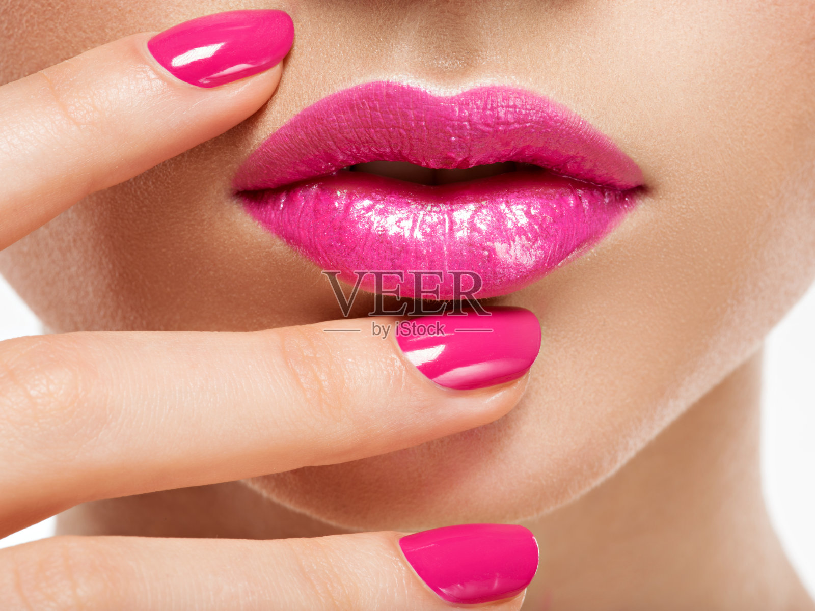 特写女人的手与粉红色的指甲靠近嘴唇。照片摄影图片