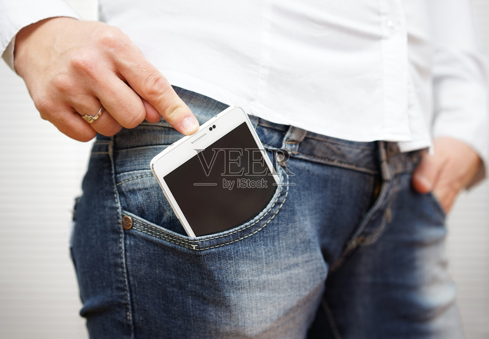 在牛仔裤口袋里推着大手机的女人照片摄影图片