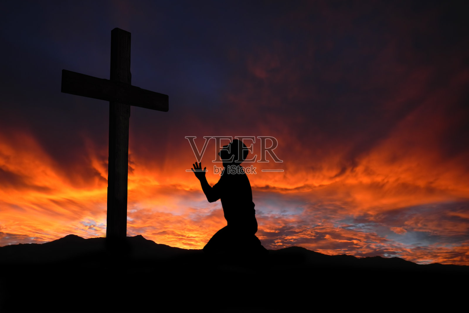 一个人的剪影祈祷一个十字架与天上的云景观照片摄影图片