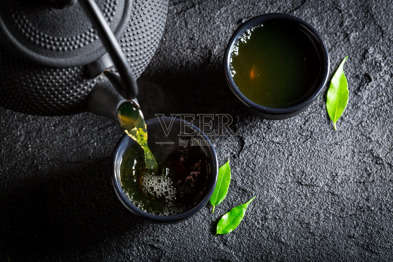 美味的绿茶配茶壶和茶杯放在黑岩上照片摄影图片