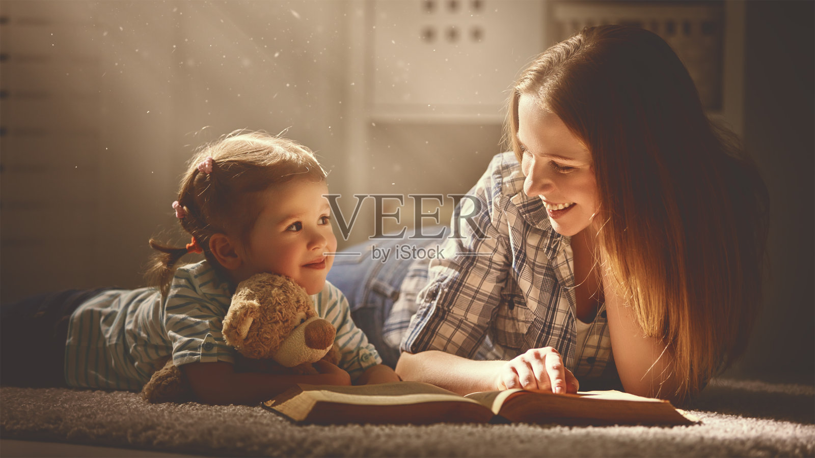 幸福的家庭妈妈和女儿晚上看书照片摄影图片