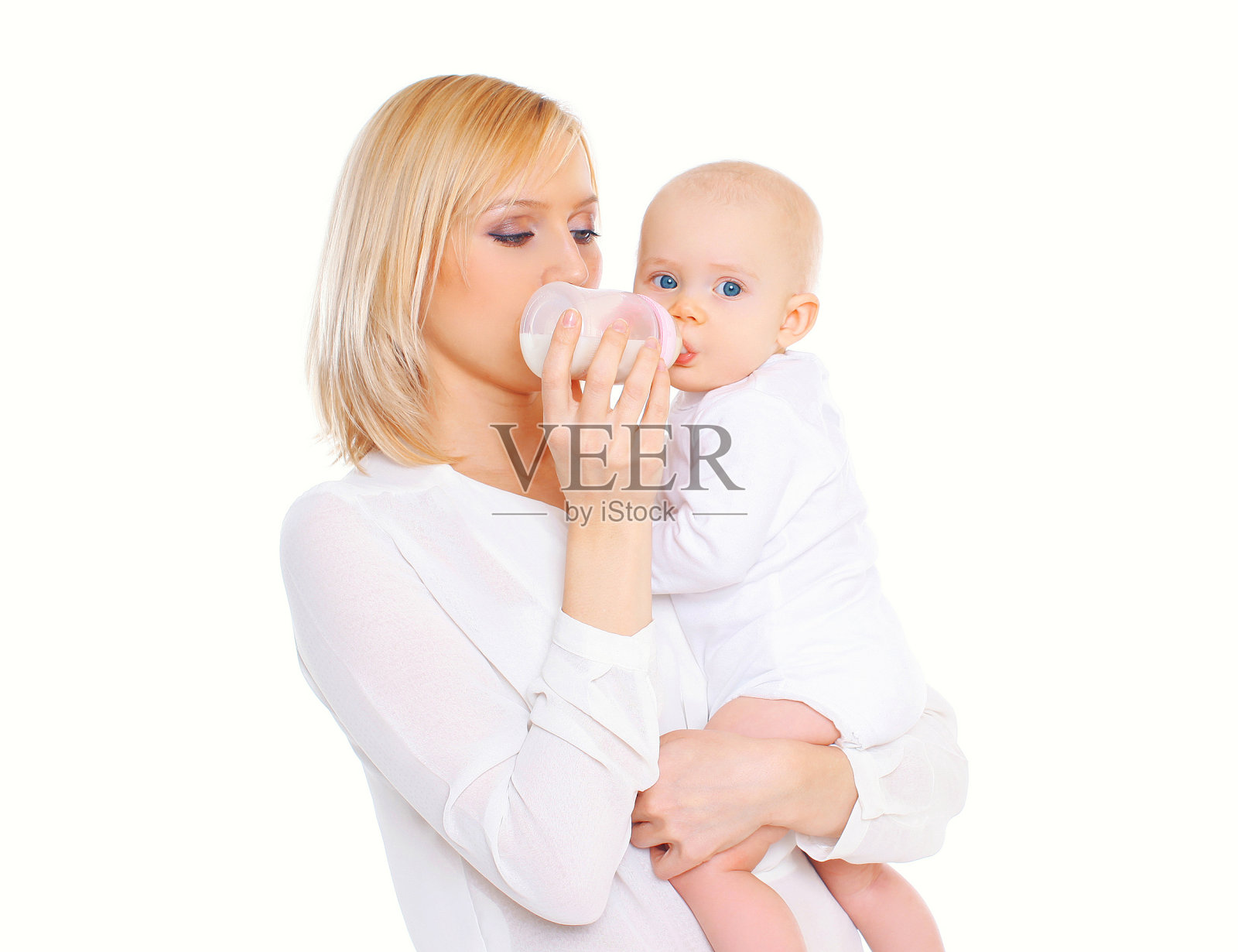 母亲用奶瓶喂她的婴儿在白色的背景照片摄影图片