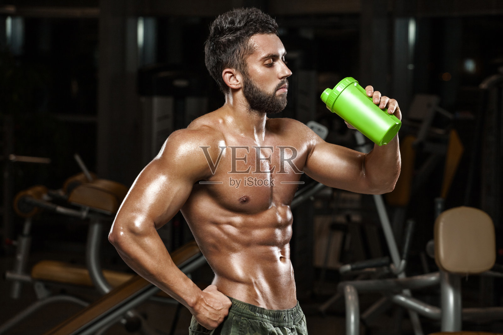 性感肌肉的男人在健身房喝水，裸体的躯干腹肌照片摄影图片
