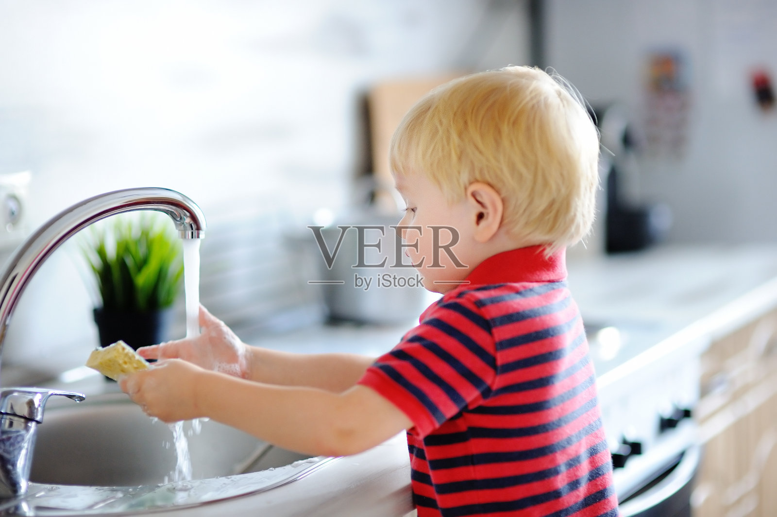 可爱的小男孩在厨房里洗盘子照片摄影图片