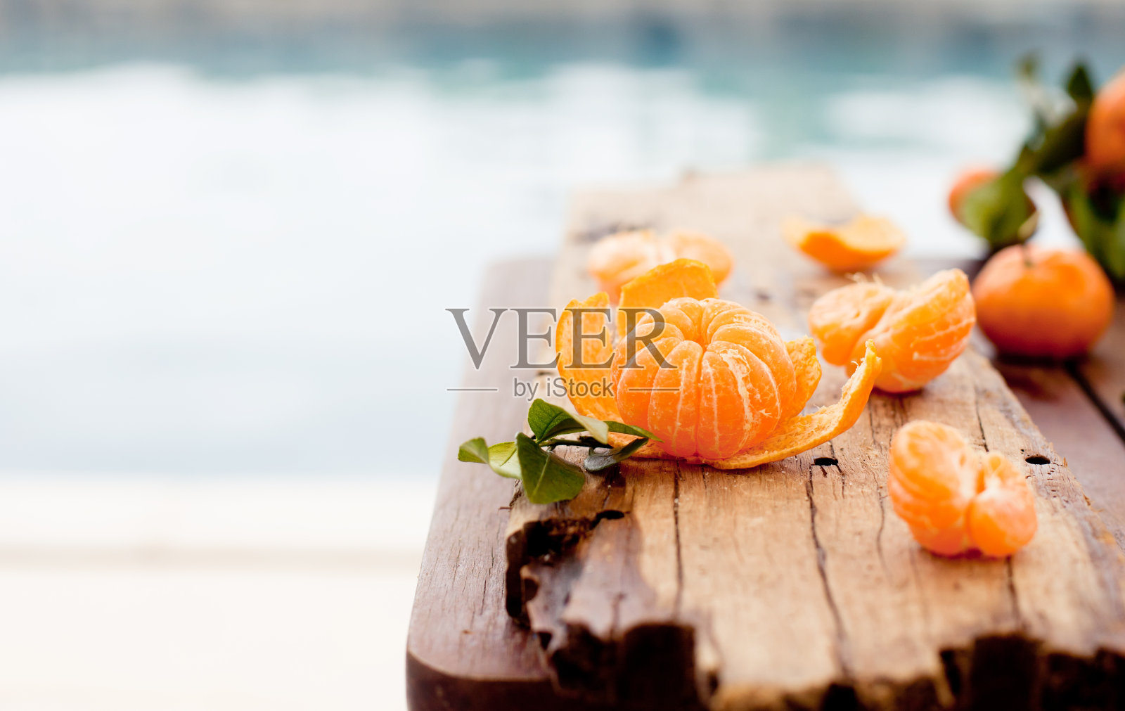 新鲜的橘子放在一张蓝色的木桌上，以大海、水景为背景照片摄影图片