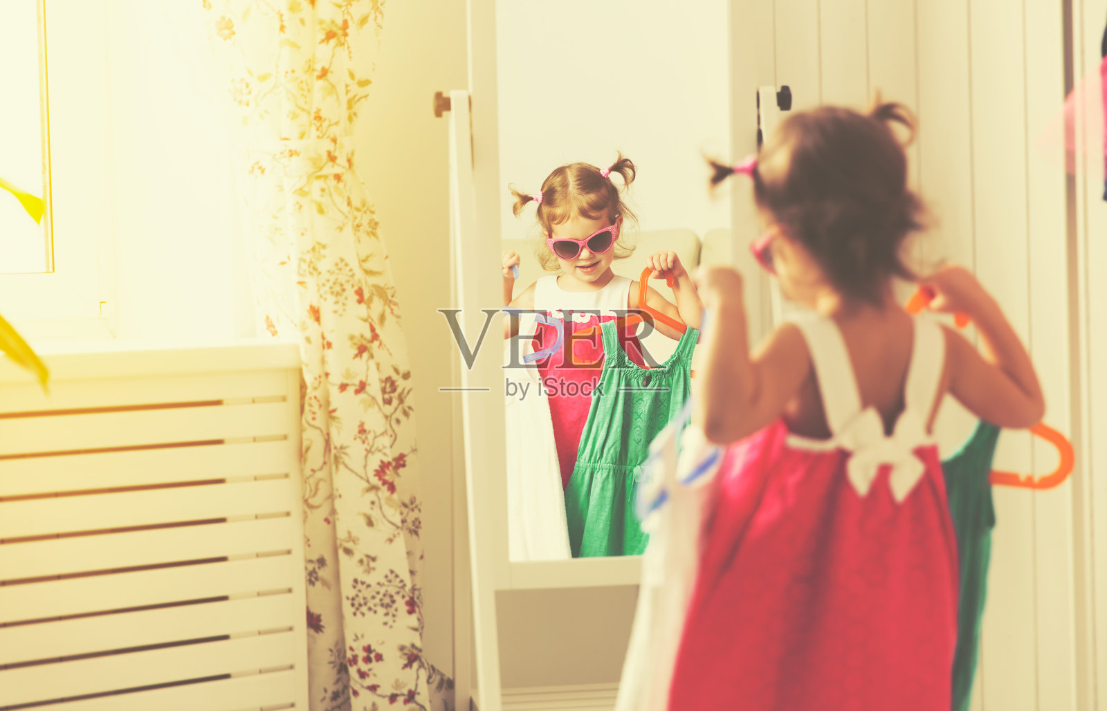 小女孩看着镜子，选择衣服照片摄影图片