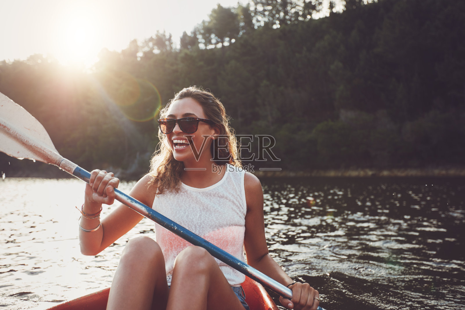微笑的年轻女子在湖上划皮艇照片摄影图片
