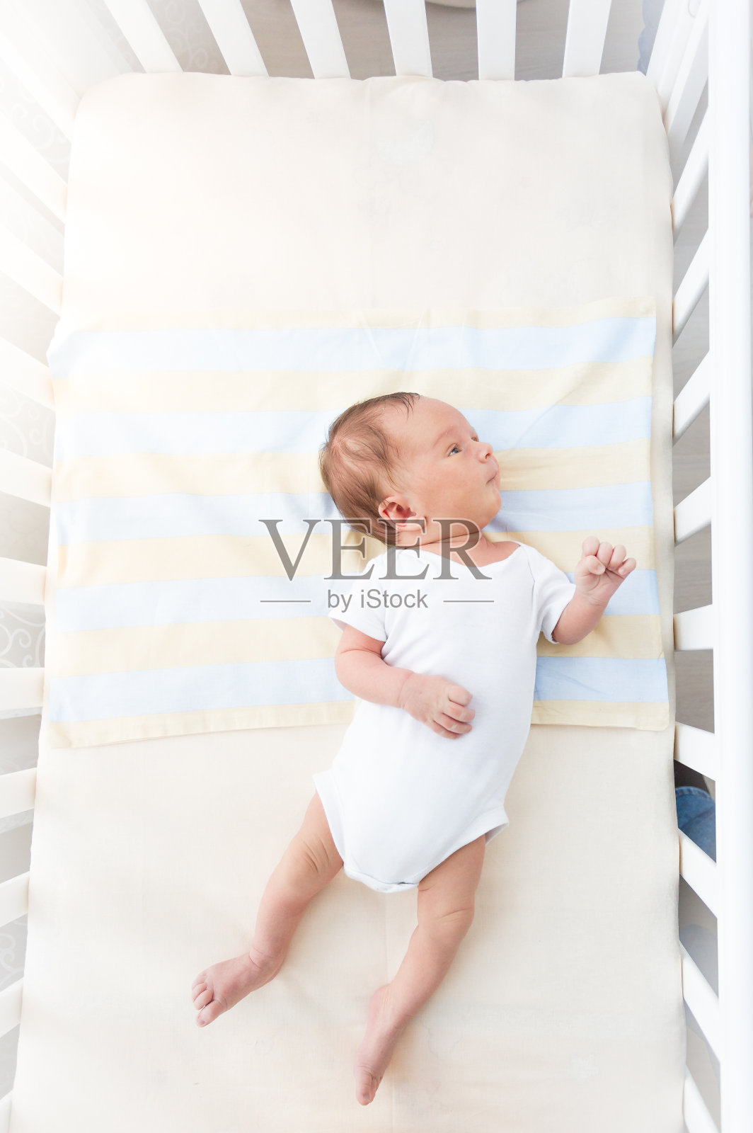 阳光明媚的日子里，可爱的婴儿躺在白色的摇篮里照片摄影图片