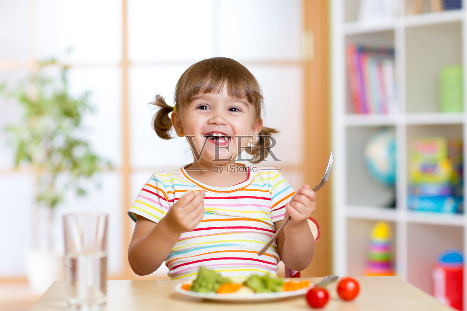 快乐的小女孩吃蔬菜。儿童健康营养照片摄影图片