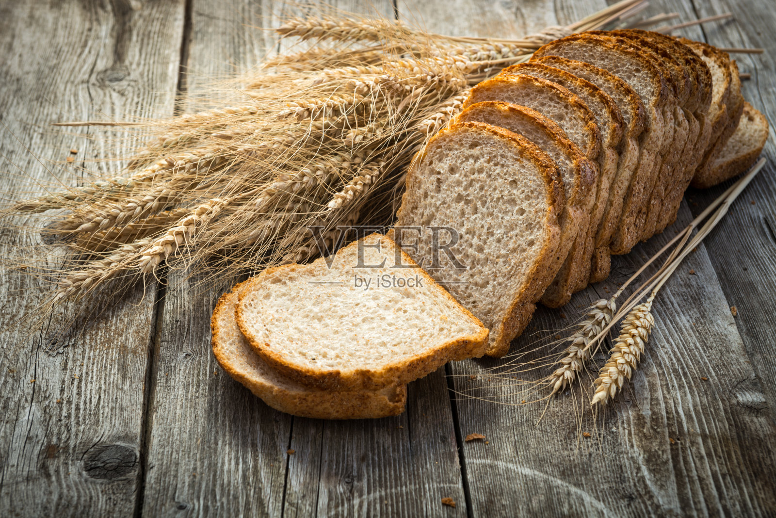 木头上放着新鲜的面包和小麦照片摄影图片