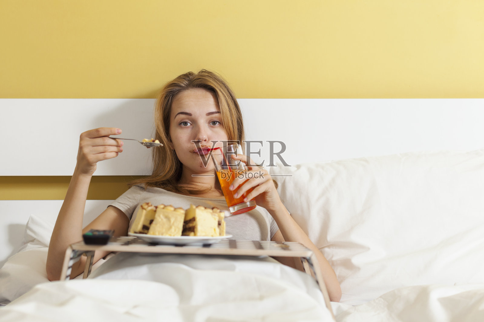 一天暴饮暴食，少女一边吃蛋糕一边喝苏打水照片摄影图片