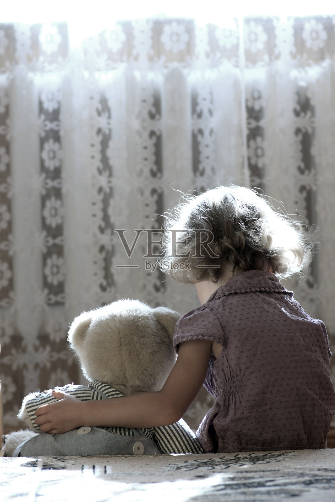 一个悲伤的小女孩抱着她的泰迪熊照片摄影图片