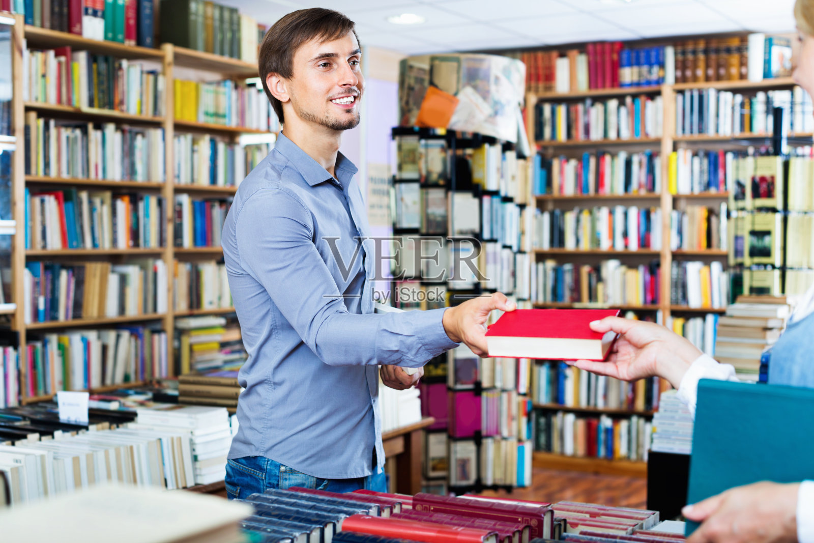 一个微笑着的年轻人正在书店里挑选书照片摄影图片