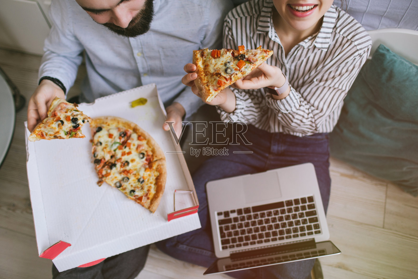 年轻的潮男女夫妇在家用笔记本电脑吃披萨照片摄影图片