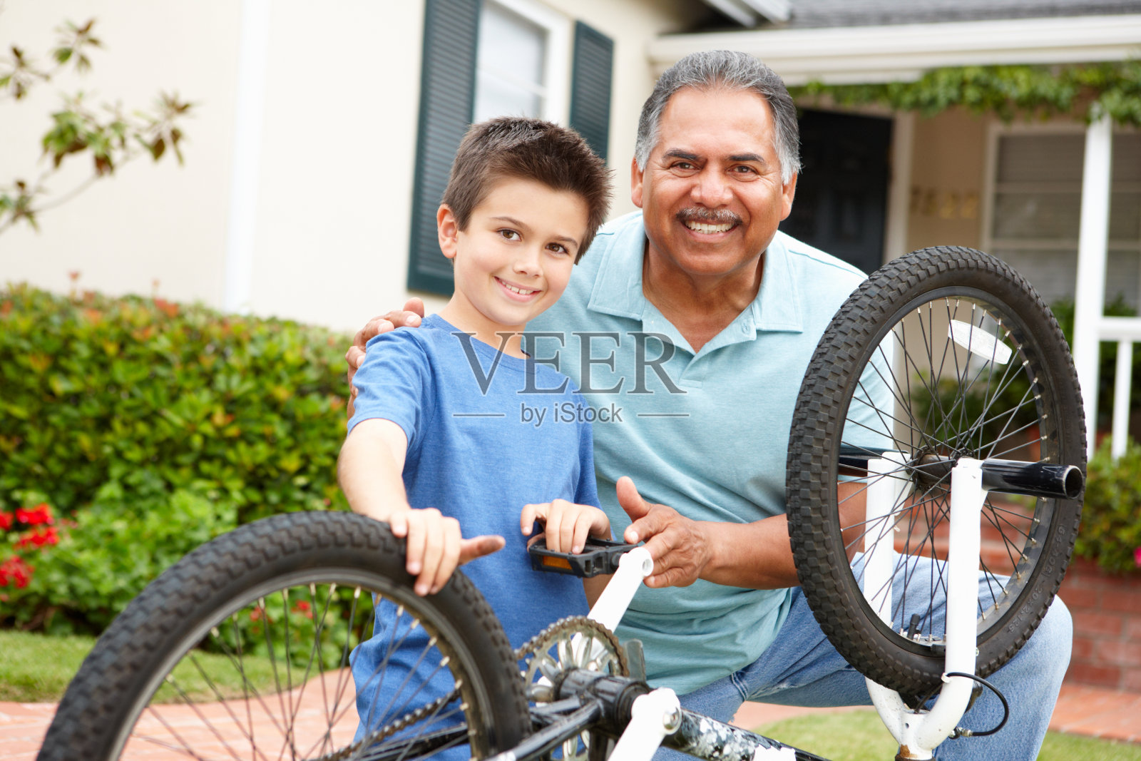 男孩和爷爷在修自行车照片摄影图片