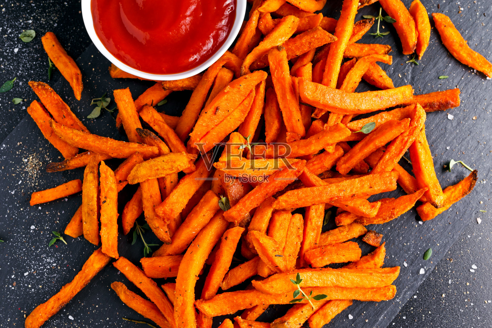 健康自制烤橙甘薯薯条配番茄酱，香草照片摄影图片